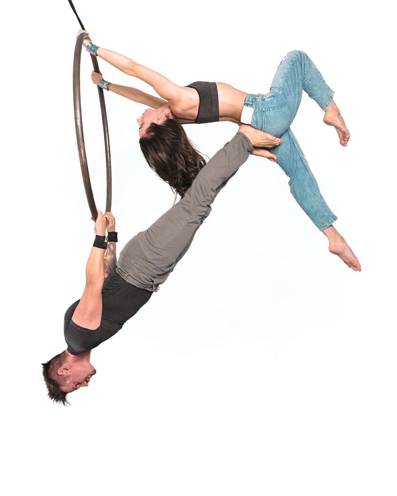 Two aerialists in a duo pose on an aerial hoop, both holding on with their hands and both wearing SneakyDeez wrist wraps