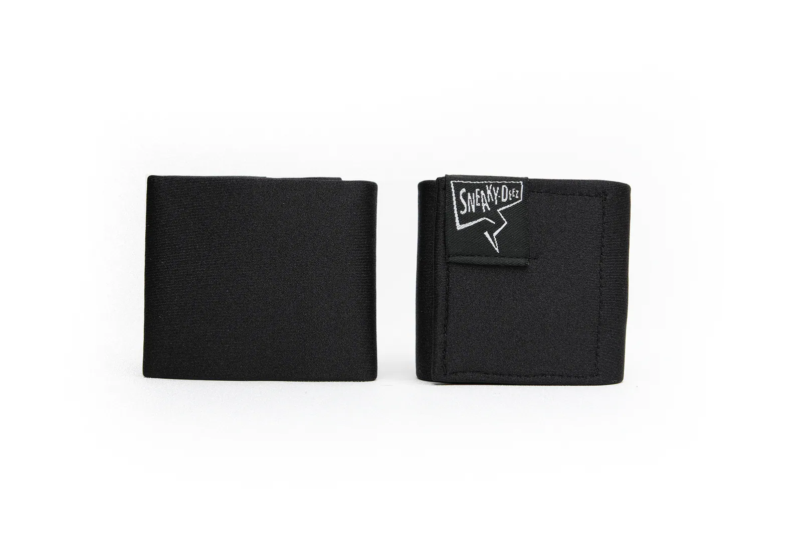 A pair of plain black SneakyDeez wrist wraps folded and standing upright on a white background, one showing the white SneakyDeez logo patch